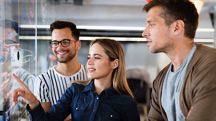 Zdjęcie grupy osób stojących przed cyfrowym wyświetlaczem