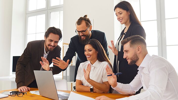 Zdjęcie grupy ludzi skupionych wokół stołu i patrzących na ekran komputera