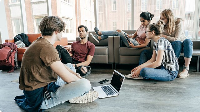 Zdjęcie grupy studentów siedzących na podłodze przed laptopem
