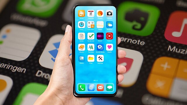 Absttrakcyjne zdjęcie telefonu trzynanego w ręce z ikonami w tle
