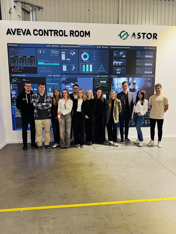 Zdjęcie grupy osób z interaktywnym panelem w tle