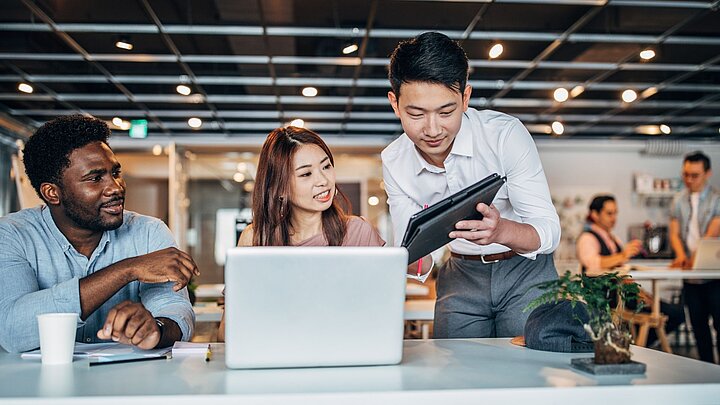 Zdjęcie grupy ludzi skupionych wokół stołu i patrzących na ekran komputera