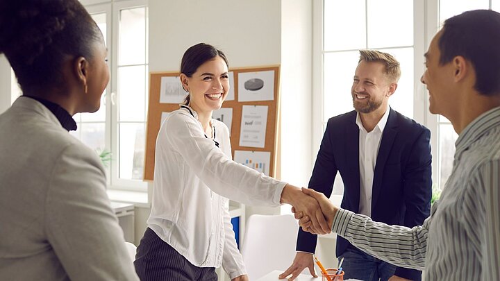 Zdjęcie czterech stojących osób z których dwie ściskają sobie dłonie