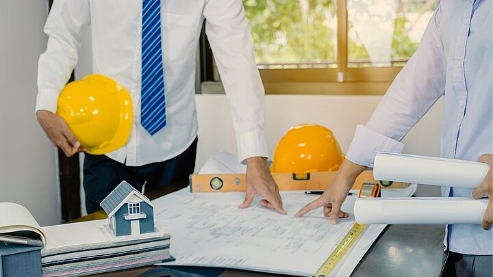 Zdjęcie dwóch osób z kaskami w rękach oglądających dokumentację