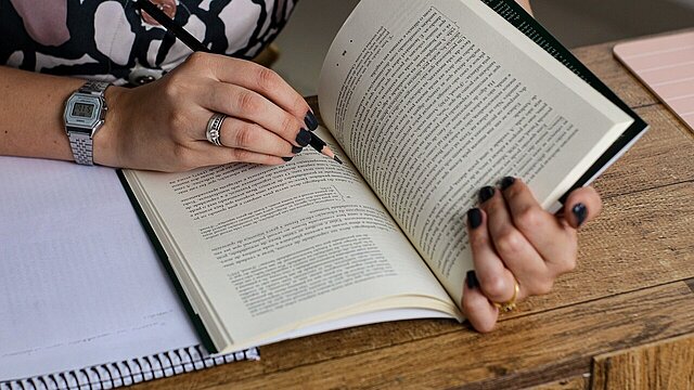 Zdjęcie książki na stole trzymanej rękami osoby