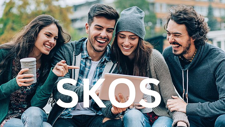 Zdjęcie grupy ludzi siedzących na ławce z napisem SKOS na froncie zdjęcia