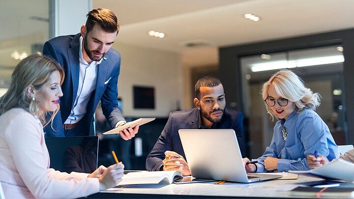 Zdjęcie drupy osób siedzących przy stole i dyskutujących ze sobą