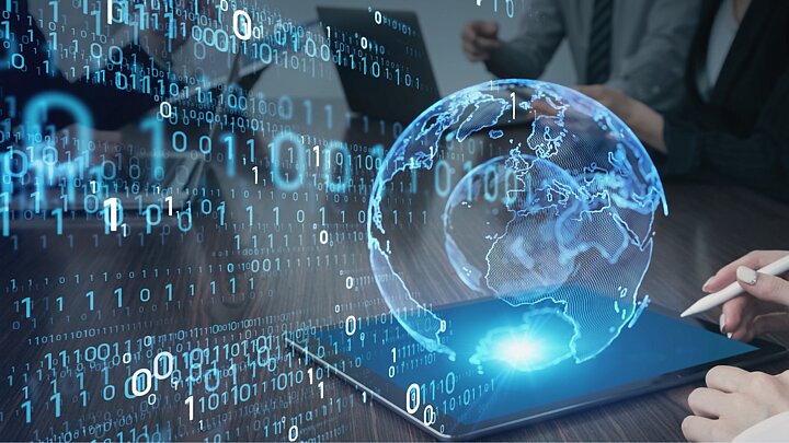 Wygenerowane cyfrowo zdjęcie tableta z któreko wypływa cyfrowa kula ziemska wraz z ciągami cyfr zero i jeden