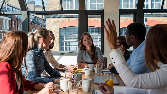 Zdjęcie grupy osób siedzących przy stole zatawionym kubkami