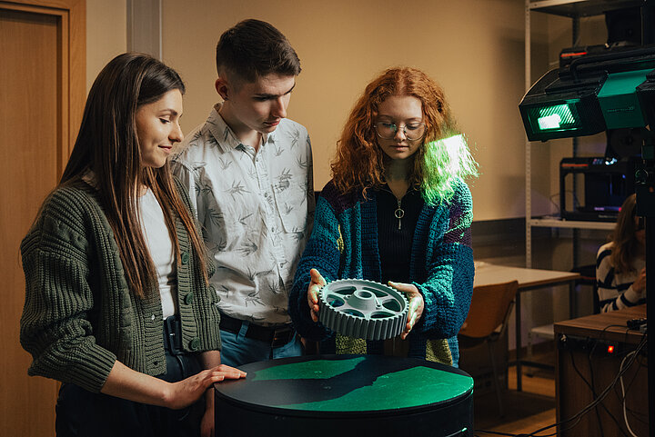 Grupa studentów trzymająca koło zębate