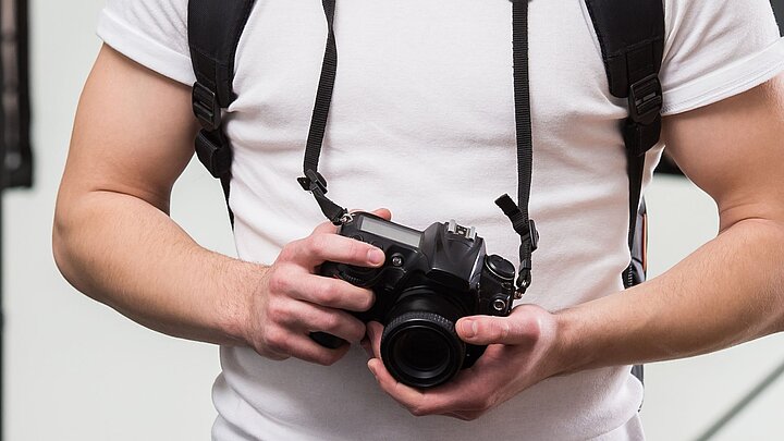 Zdjęcie mężczyzny z aparatem fotogramicznym na szyi