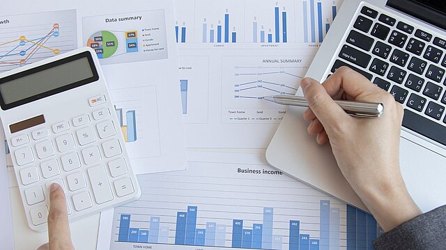 Zdjęcie stołu od góry na którym leży kalkulator klawiatura i sterty dokumentów