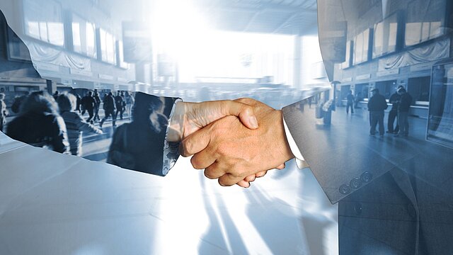 Grafika Przewdstawiająca ściśniete dłonie dwóch osób na tle tłumu ludzi