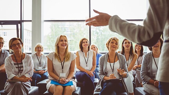 Zdjęcie grupy słuchaczy siedzących na krzesłach i patrzących na wykładowcę