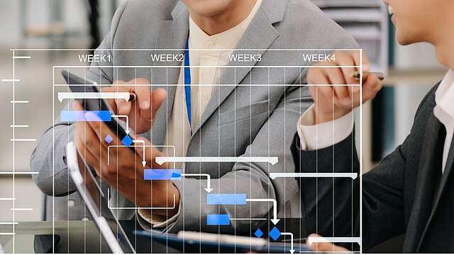 Zdjęcie dwóch osób przed przeźroczystym zdygitalizowanym ekranem piszących na nim