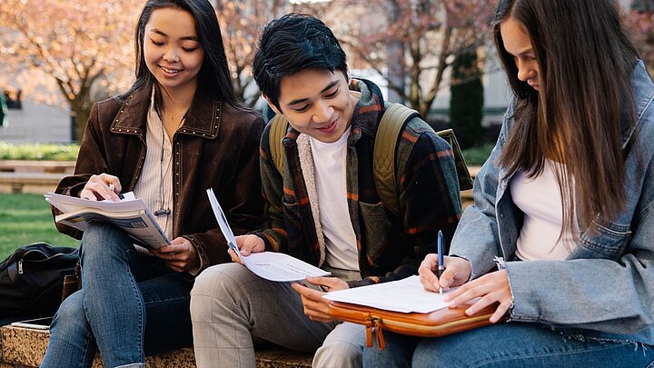 Zdjęcie trzech młodych osób siedzących na ławce w parku