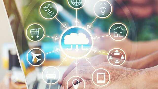 Zdjęcie dłoni piszących na klawiaturze z wygenerowanymi cyfrowo grafukami w formie ikon na pierwszym planie