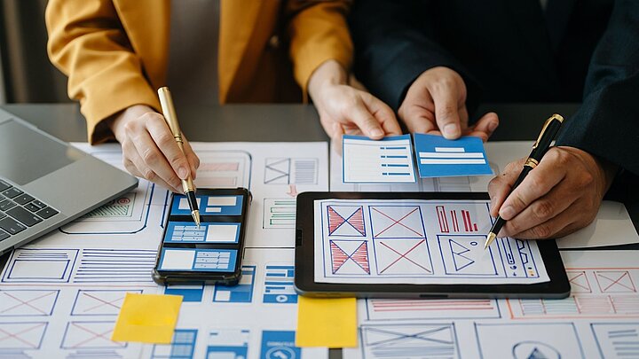 Zdjęcie stołu na którym są rozłożone dokumenty telefon i tablet