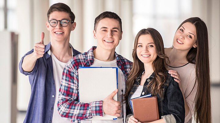 Zdjęcie czterech studentów i trzymających w rękach różne dokumenty