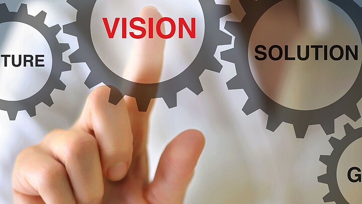 Zdjęcie dłoni wskazującej na koło zebate z napisem vision