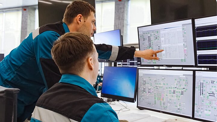 Zdjęcie dwóch osób siedzących przed monitorami