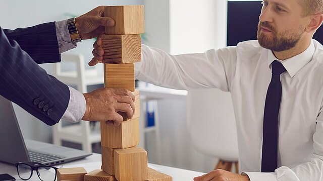 Zdjęcie dwóch osób układających drewniane klocki