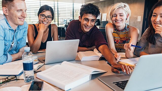 Zdjęcie grupy osób siedzących przy stole i rozwiązujących projekt