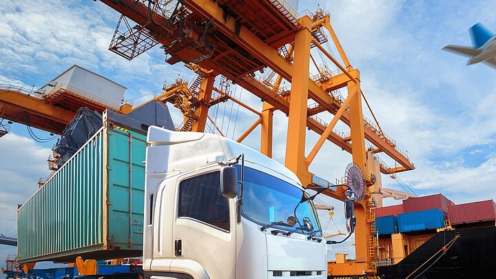 Grafika przedstawiająca samochód a w tle duży żuraw dźwigowy