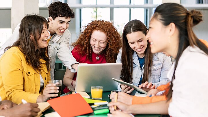 Zdjęcie grupy osób skupionych wokół stołu i patrzących na laptop