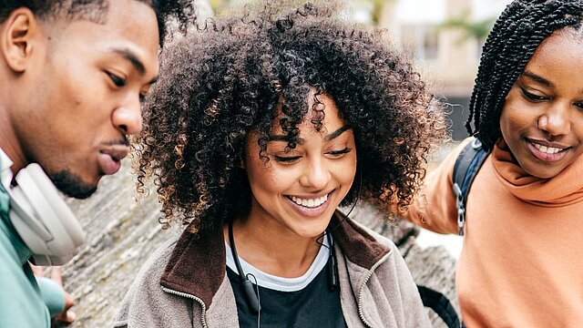 Zdjęcie trzech studentów uśmiechających się i patrzących w jeden punkt