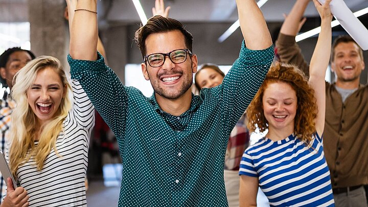 Zdjęcie drupy osób z rękami uniesionymi do góry z geście zwycięstwa