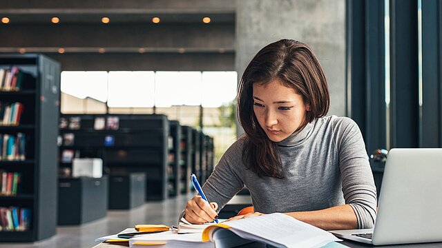 Zdjęcie osoby siedzącej przy stole i czytającej książkę
