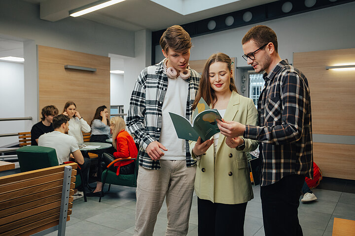 grupa studentów przeglądających książkę