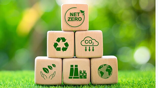 Grafika przedstawiająca klocki z ikonami na tle trawnika