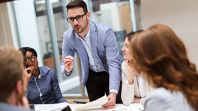 djęcie osób siedzących przy stole na naradzie i dyskutujących