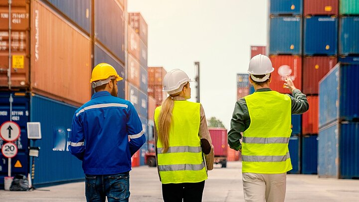 Zdjęcie trzech osób stojącym pomiędzy kontenerami