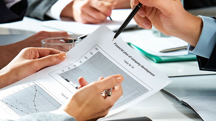 Zdjęcie osób siedzących przy stole i czytających dokumenty