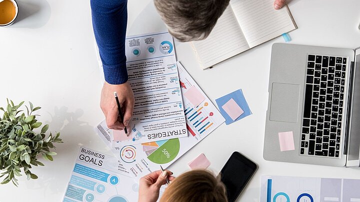 Zdjęcie z góry stołu dwóch osób przeglądających dokumenty