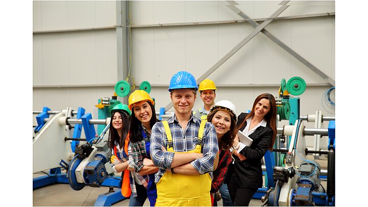 Zdjęcie grupy ludzi w ubraniach roboczych na hali produkcyjnej