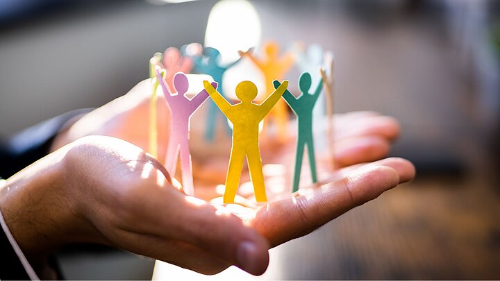 Grafika na której na dłoni stoją wygenerowane kształty ludzi