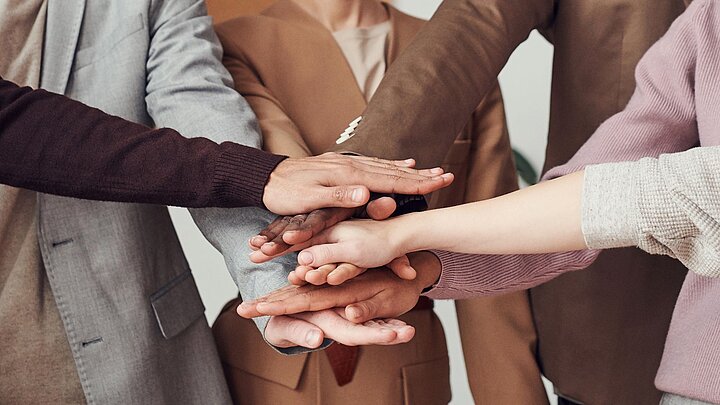 Zdjęcie grupy osób trzymających jedna na drugiej swoje ręce