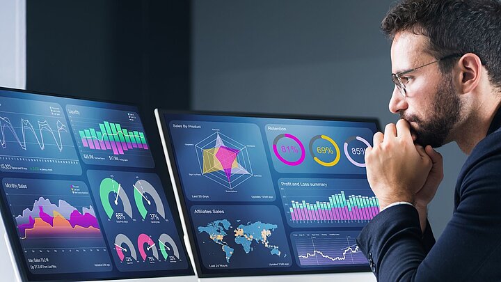 Zdjęcie osoby siedzącej przed dwoma monitorami