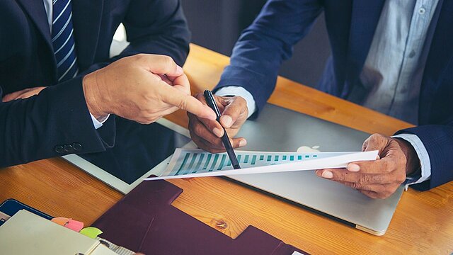 Zdjęcie dwóch mężczyzn siedzących przy stole i analizujących dane