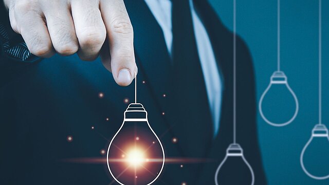 Abstrakcyjne zdjęcie dłoni trzymającej wygenerowaną cyfrowo żarówkę