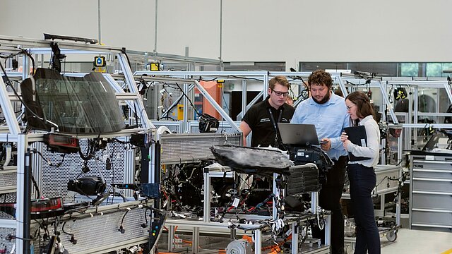 Zdjęcie trzech osób stojących przed maszyną i ją oglądających