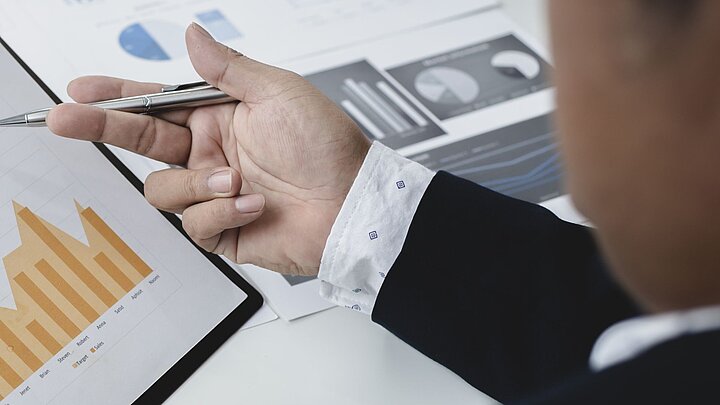 Zdjęcie ręki trzymającej długopis wskazującej na wykres
