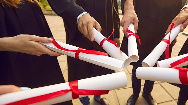 Zdjęcie zwiniętych w rulony dyplomów skierowanych do siebie i tworzących rozetę