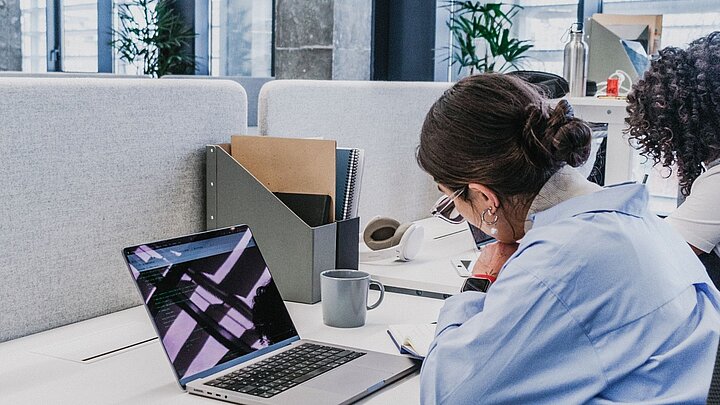 Zdjęcie kobiety siedzącej przy stole na którym leży otwarty laptop