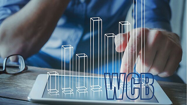 Zdjęcie dłoni człowieka wskazującej palcem na laptop z którego wychodzi wykres słupkowy i napis wcb